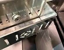 MARELI SYSTEM / CALDAIA LEGNA LCG LAMBDA – L’immagina illustra lo sportello su sui è montato un piccolo contenitore al cui interno viene messo del pellet che servirà come innesco per l'accensione automatica della combustibile, L'accensione del pellet avviene per surriscaldamento a mezzo di una candeletta, la stessa che normalmente viene utilizzata nelle stufe e/o delle caldaie a pellet.